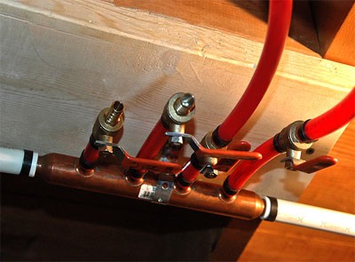 How to install PEX tubing system. PEX plumbing copper manifold installed in basement with red non-Barrier PEX tubing.